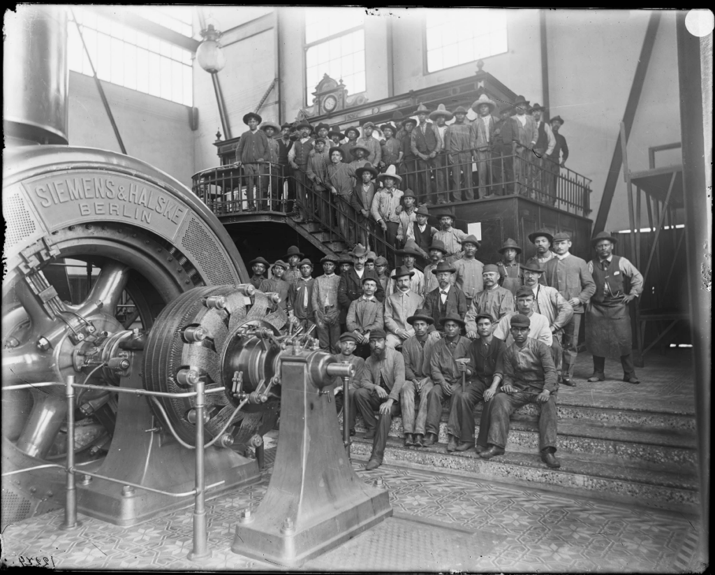 Workers at a factory pose for a black and white group photo